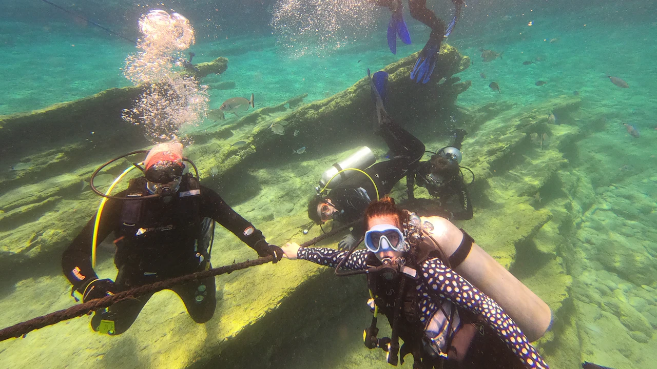 Two divers kneeling on a sandy bottom in shallow water