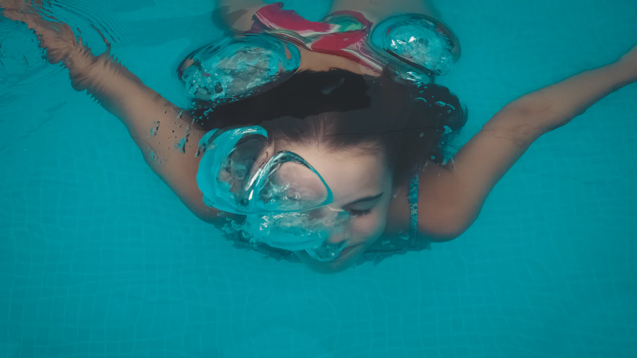 Girl in a mask swimming underwater in a pool