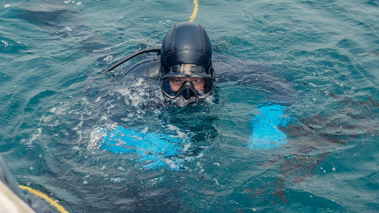 Scuba diver at the surface in a mask and hood before going down