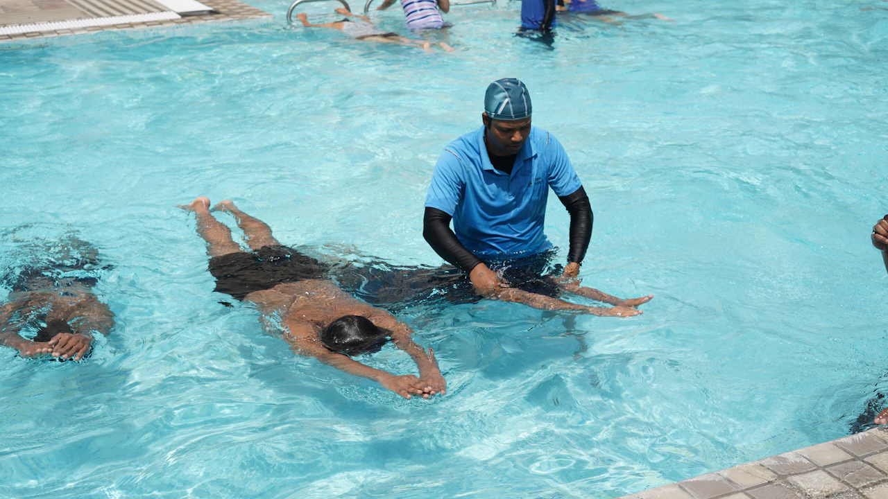 Swim instructor guiding a student floating face down in an outdoor pool