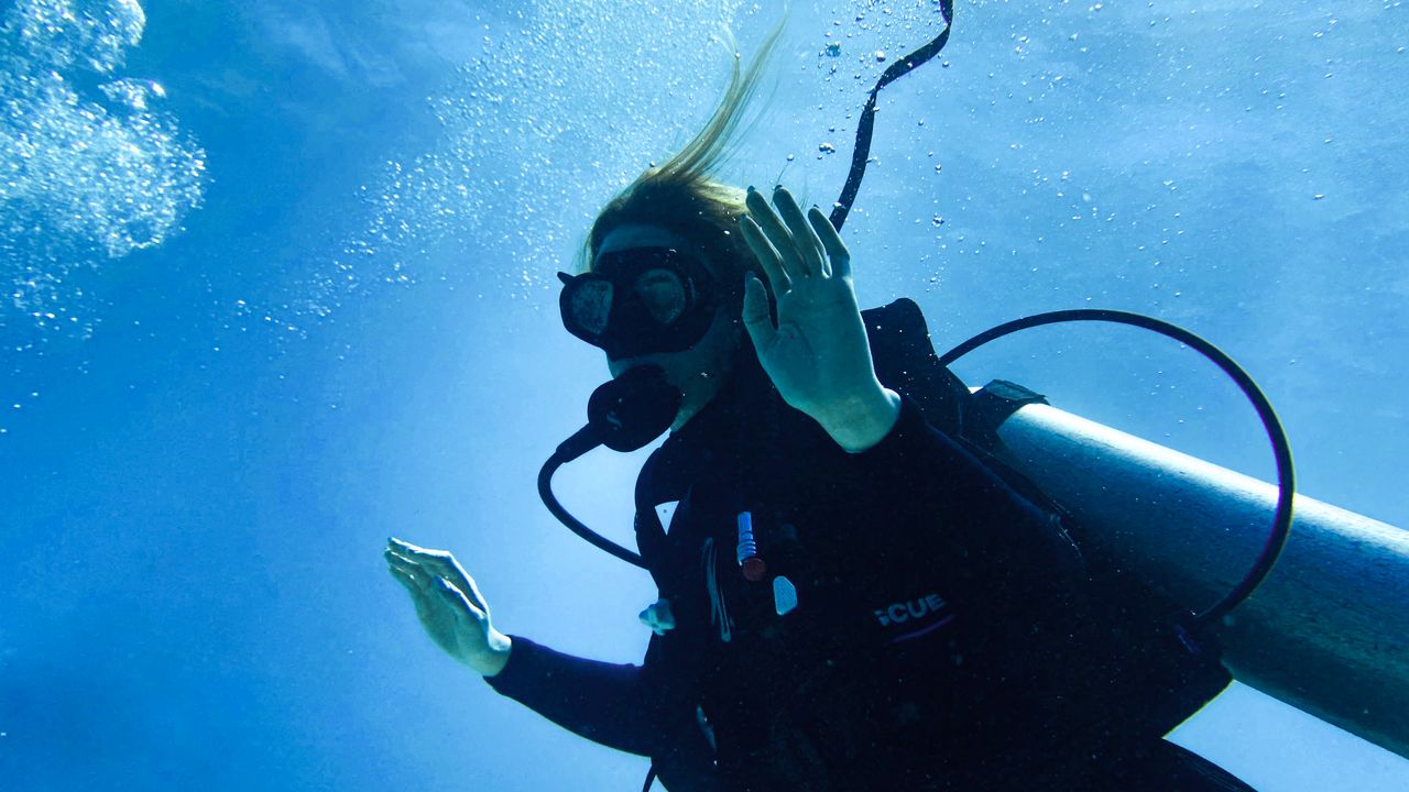 Scuba diver making a hand signal to a buddy underwater