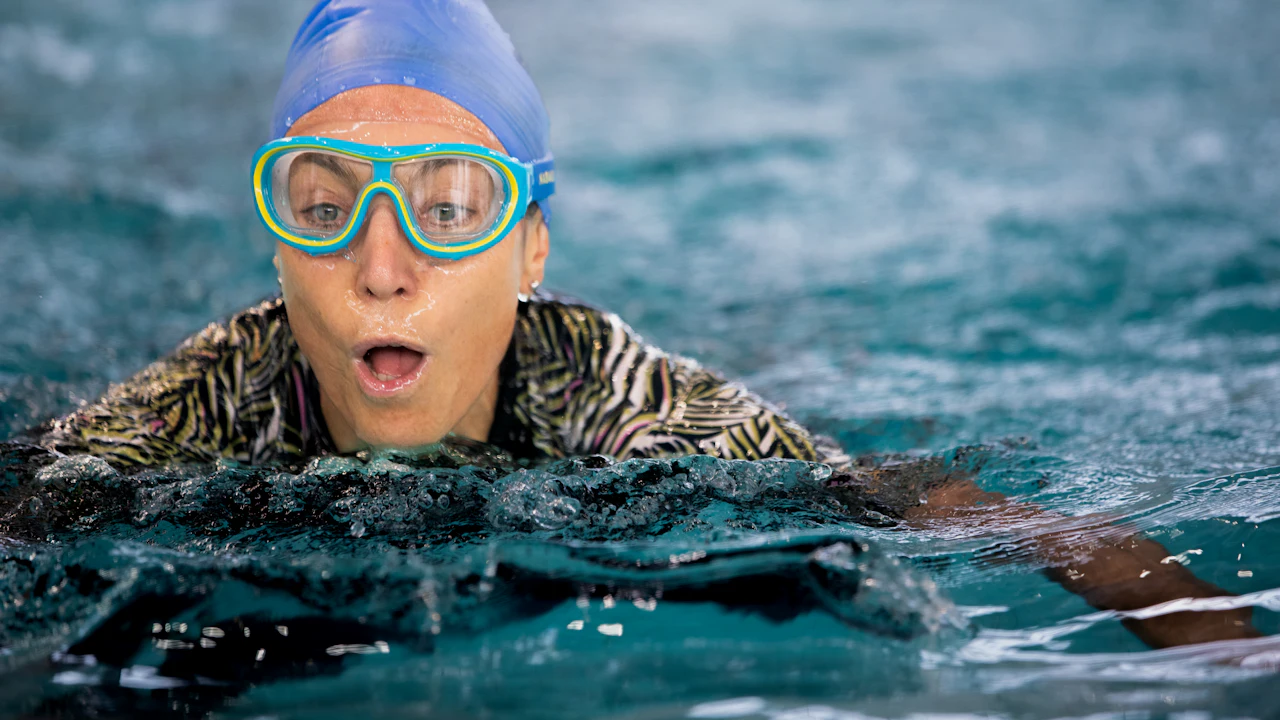 Surprised swimmer in a cap and goggles in a pool