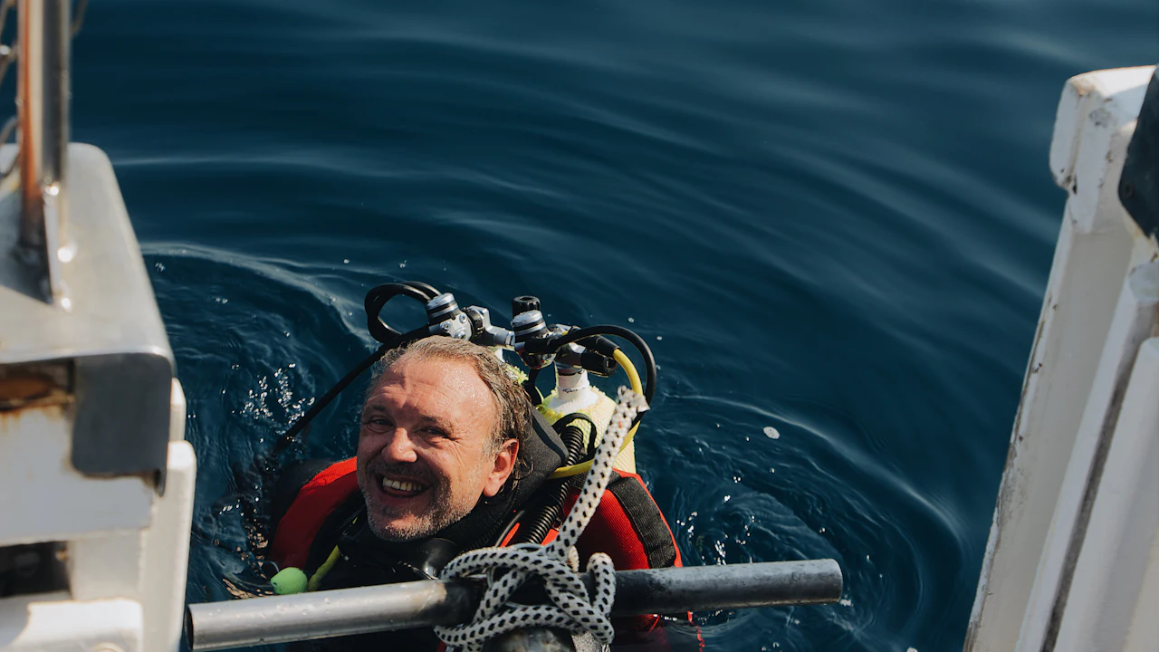 Smiling diver in the water beside a boat at the end of a dive
