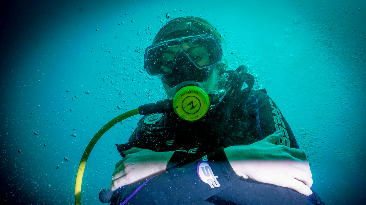 Diver in a mask holding a yellow regulator