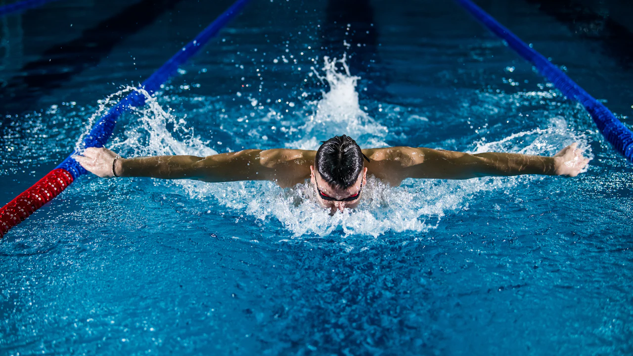 Swimmer doing butterfly stroke in a lane of an outdoor pool
