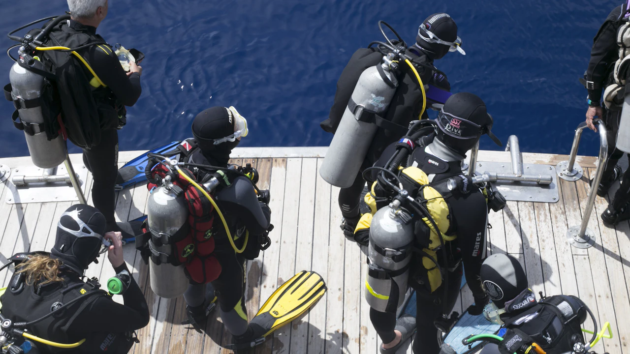 Group of scuba divers gearing up on a boat deck