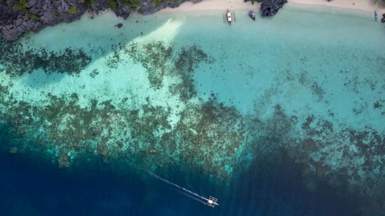 Aerial view of a boat over a shallow reef and turquoise water