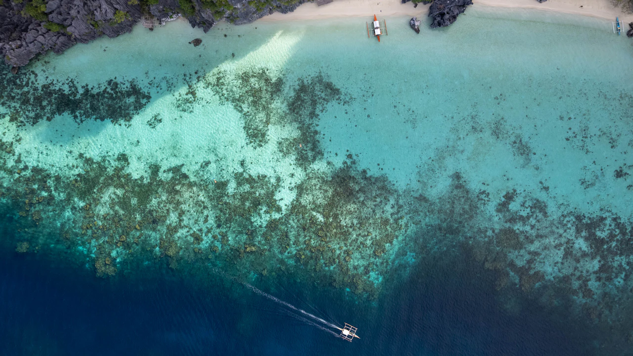Aerial view of a boat over a shallow reef and turquoise water