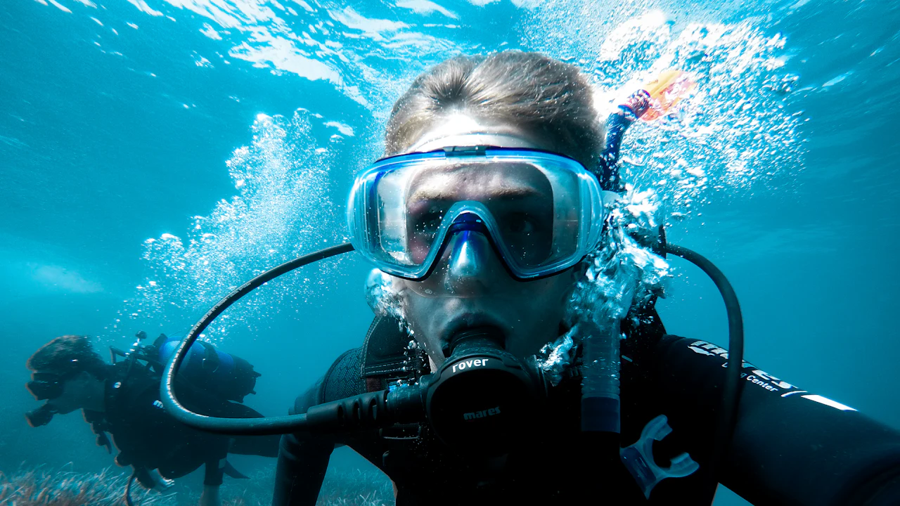 Scuba diver in a mask and regulator facing the camera underwater
