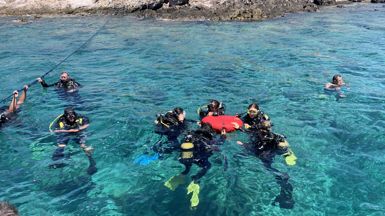 Group of scuba divers gathered at the surface around a red marker buoy