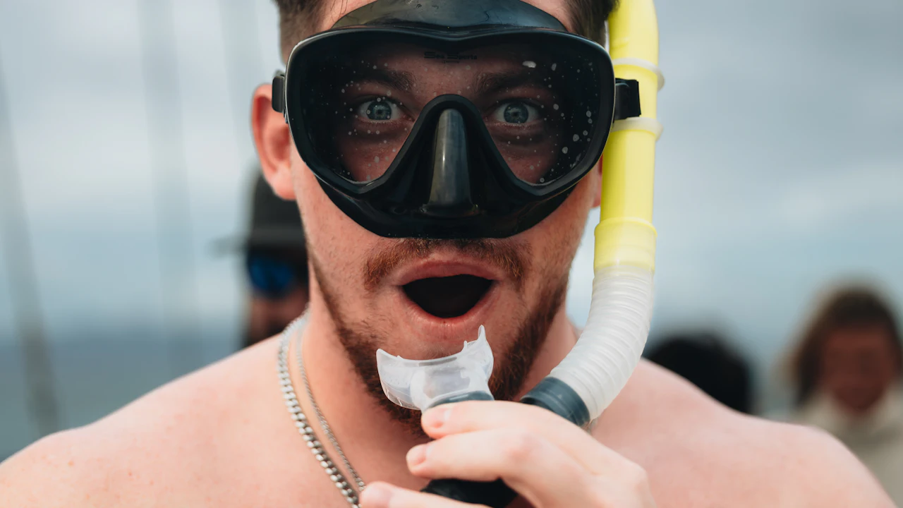 Man in a dive mask holding a snorkel mouthpiece