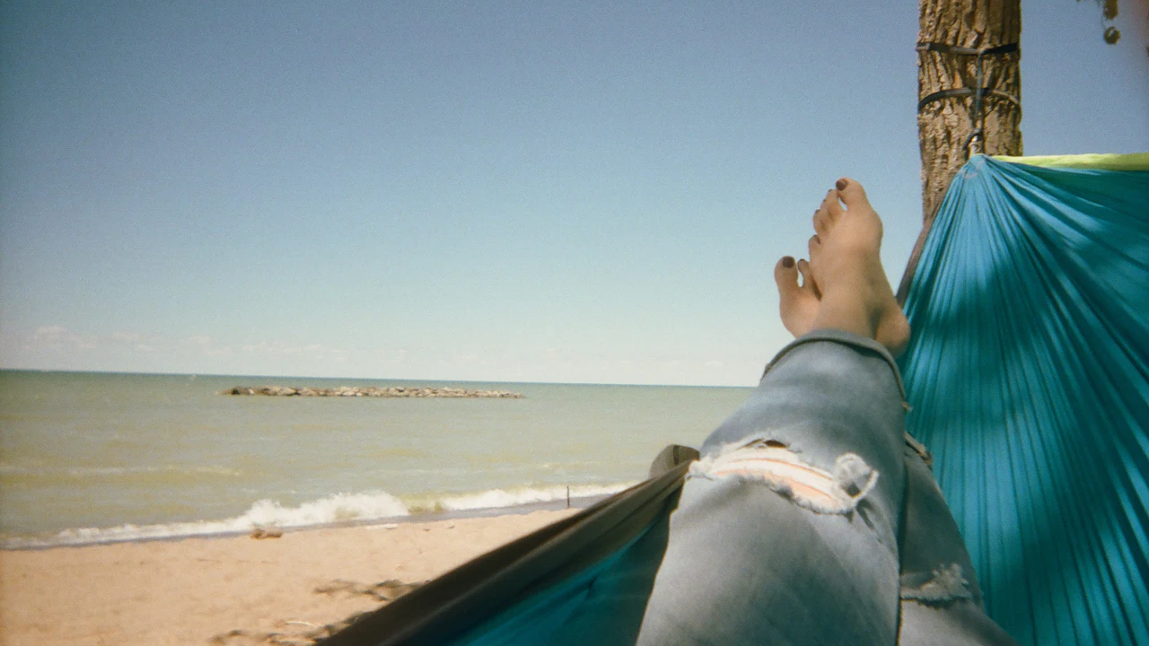 Person resting in a hammock on a sunny beach