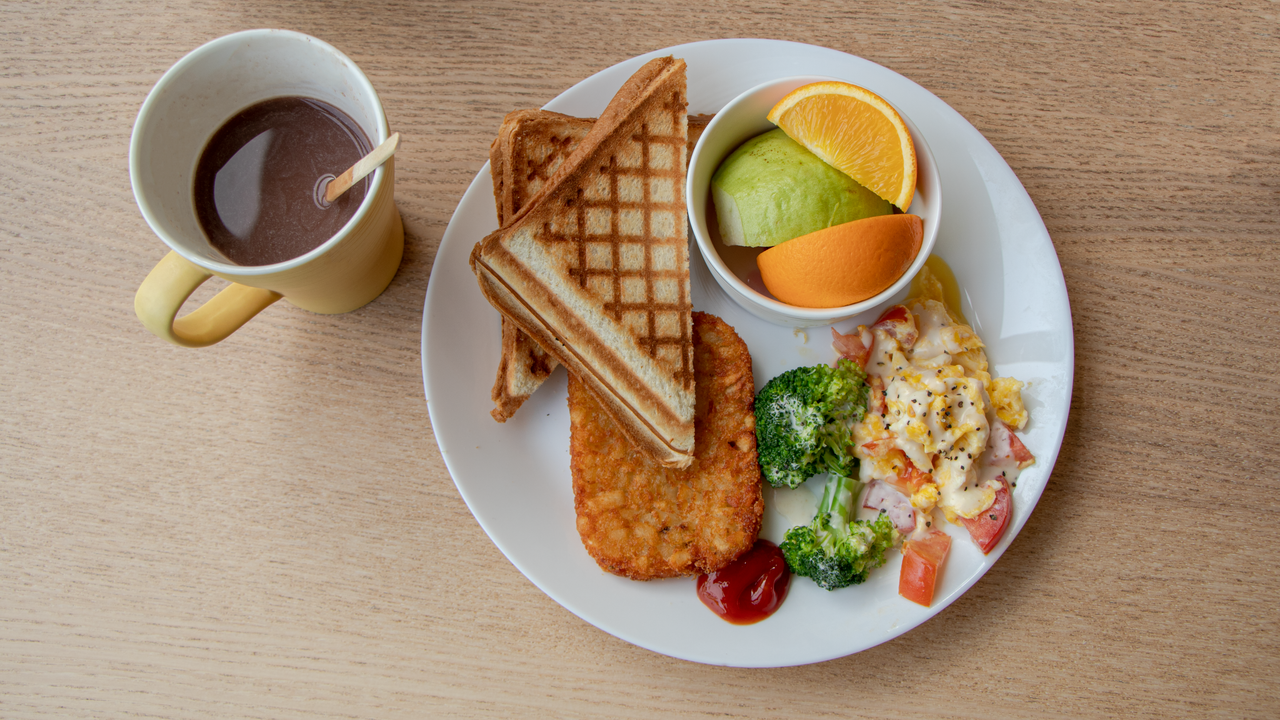 Light breakfast of toast, fresh fruit and coffee on a wooden table