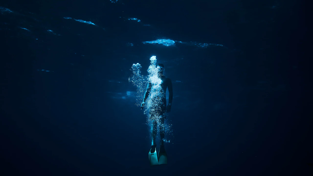 Diver rising through dark blue water
