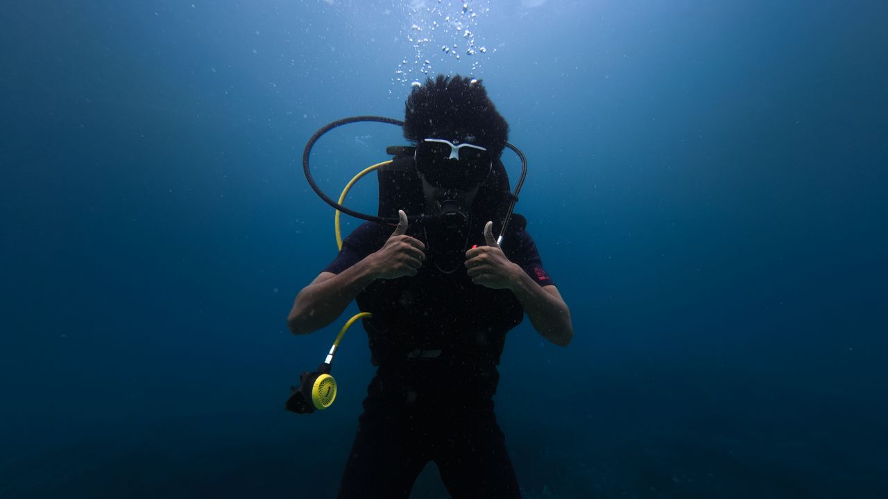 Scuba diver underwater making a hand signal toward the camera
