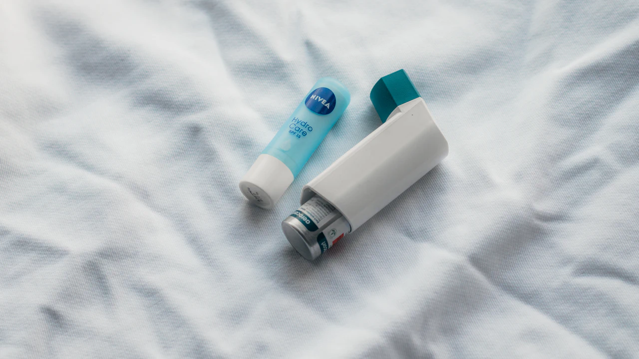 Two asthma inhalers lying on a white sheet