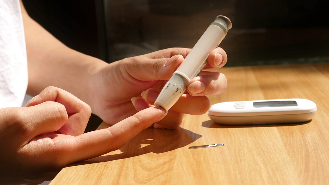 Person testing blood sugar with a finger prick and a handheld glucose meter