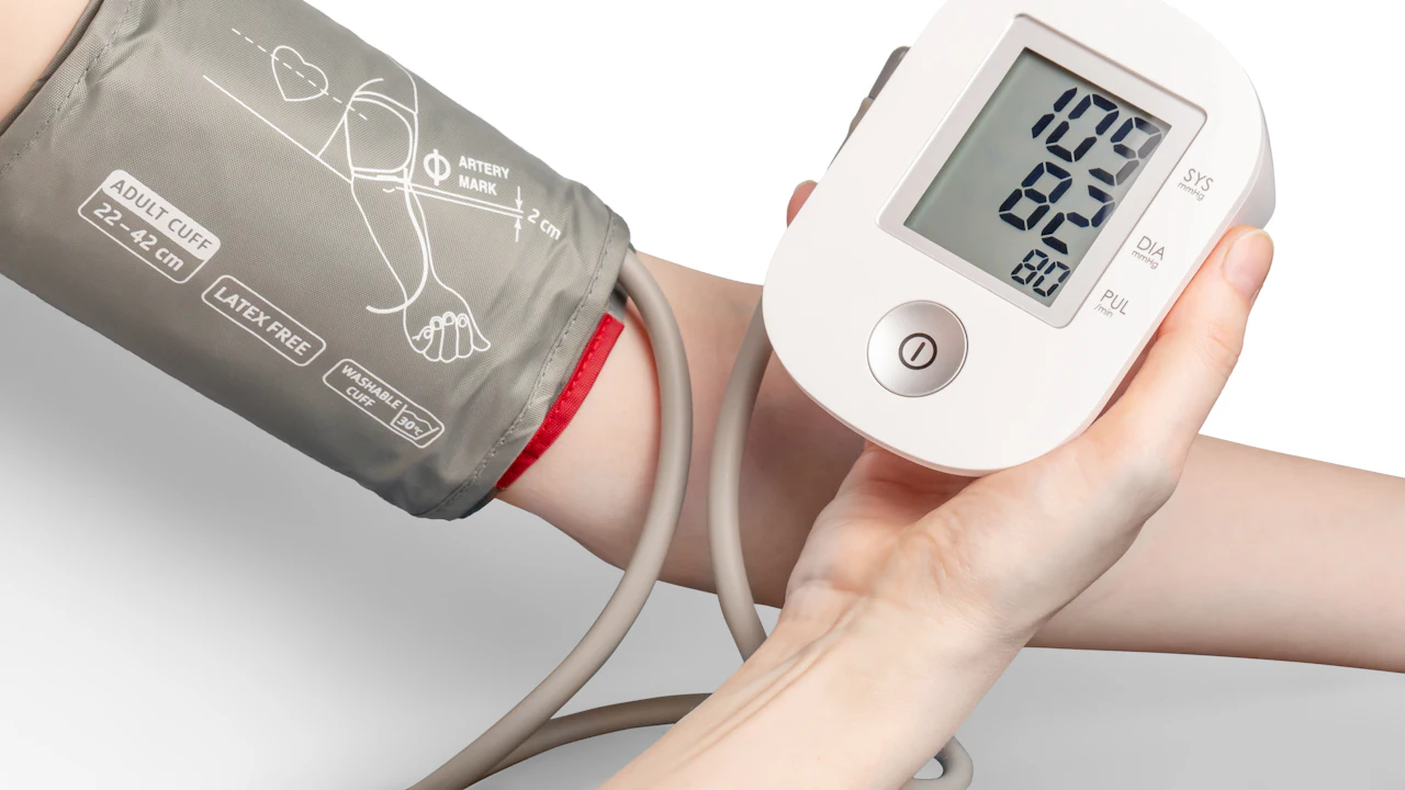Digital blood pressure monitor with a cuff wrapped around an adult's upper arm