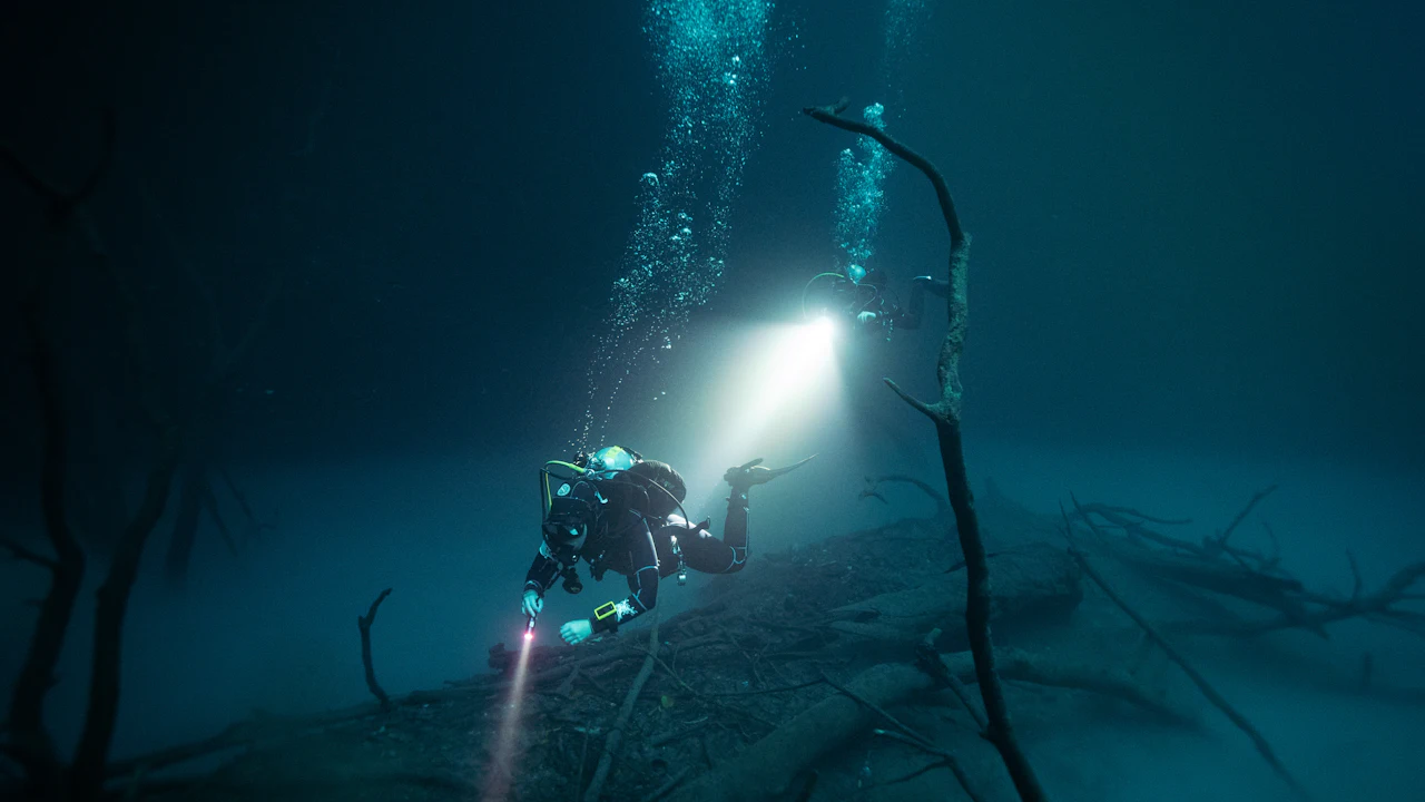 Diver holding a bright dive light in dark water at night