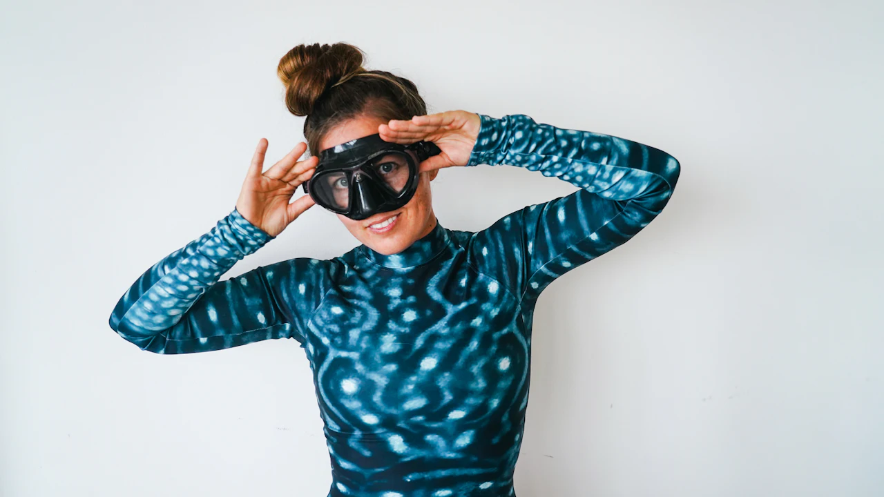 Woman holding a diving mask against her face to test the seal