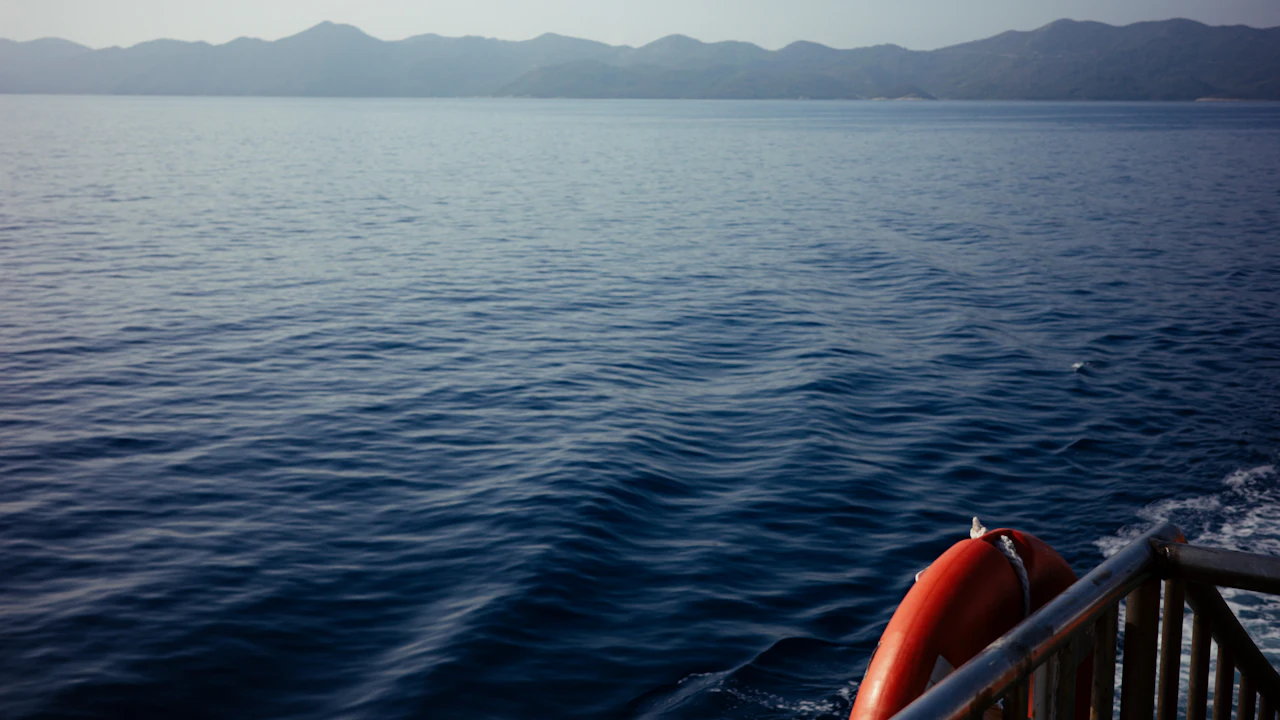 Calm sea and distant hills seen from the stern of a boat