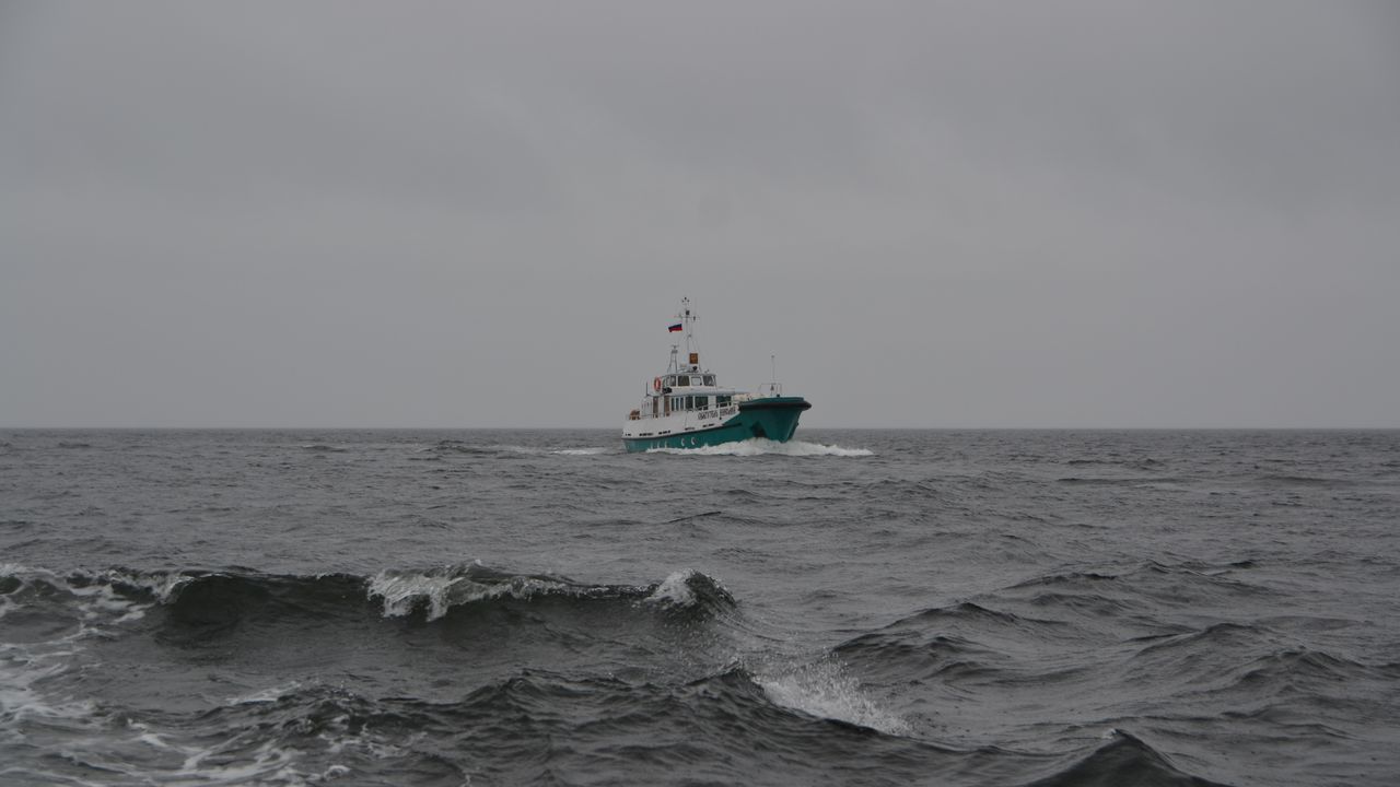 Small boat riding over grey choppy waves