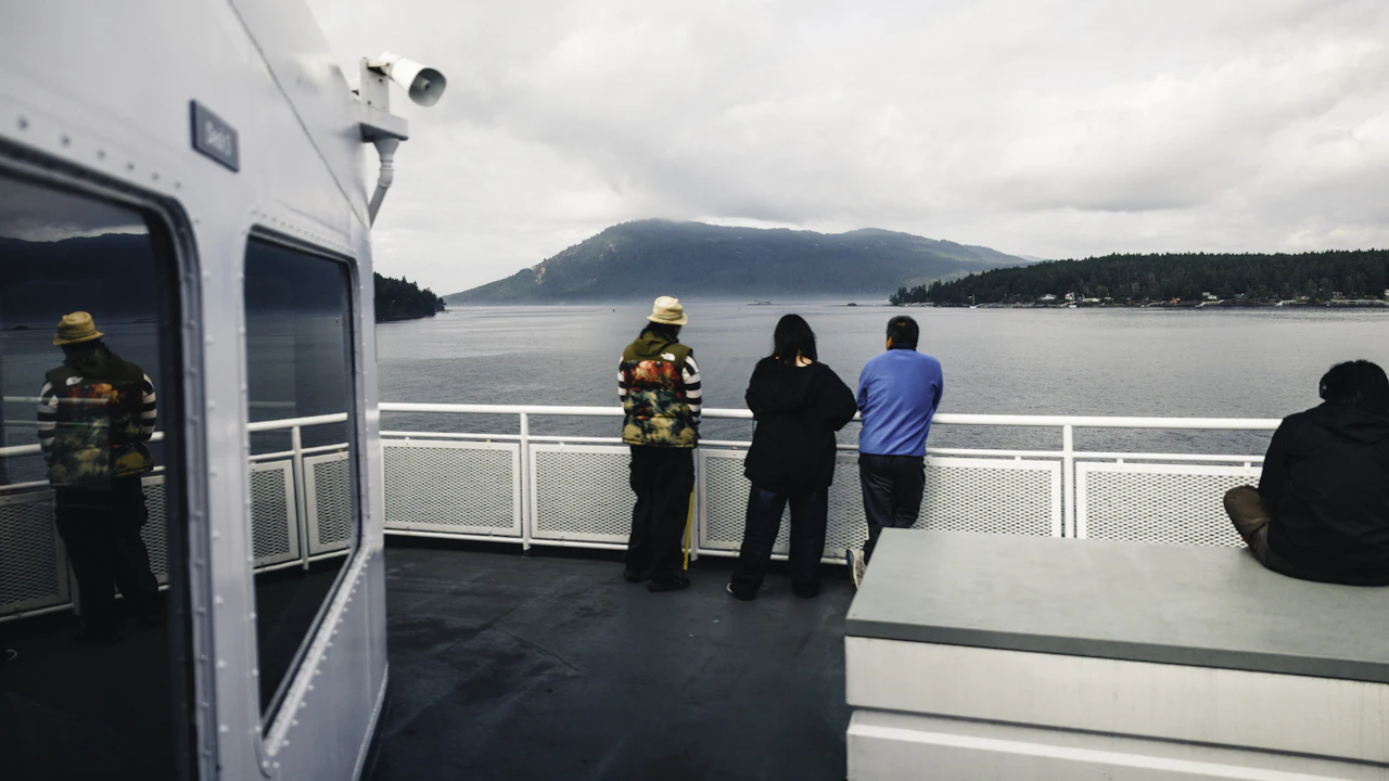 Passengers standing at the rail of a ferry deck looking at the sea