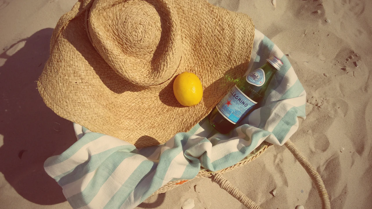 Sun hat, a lemon and a water bottle on a beach towel