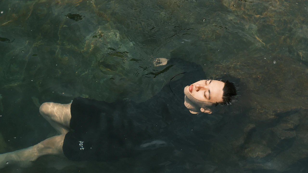 Man floating on his back in calm dark water