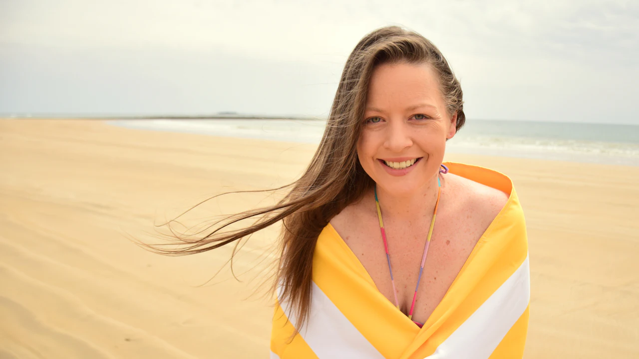 Smiling woman wrapped in a towel on a beach