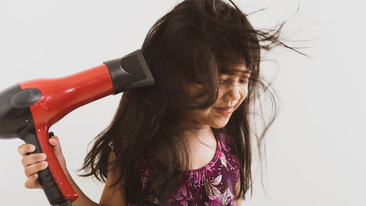 Child drying her hair with a hair dryer