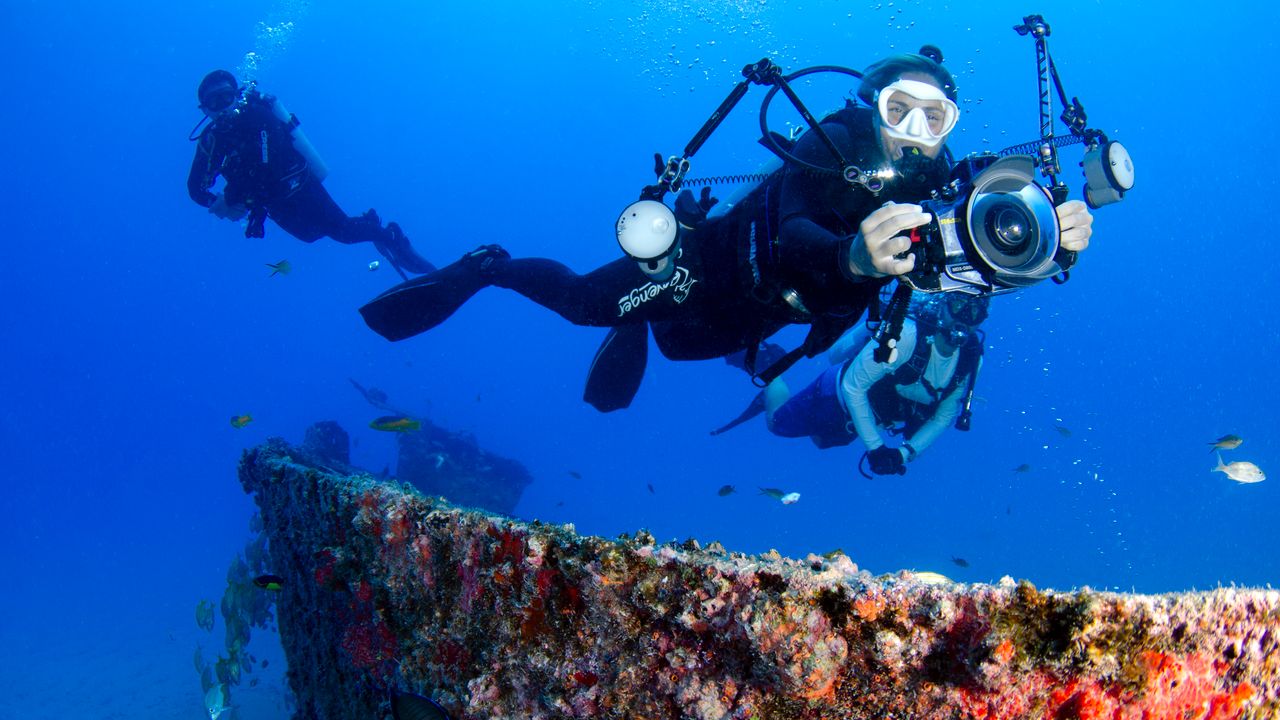 Underwater photographer with a camera rig over a wreck