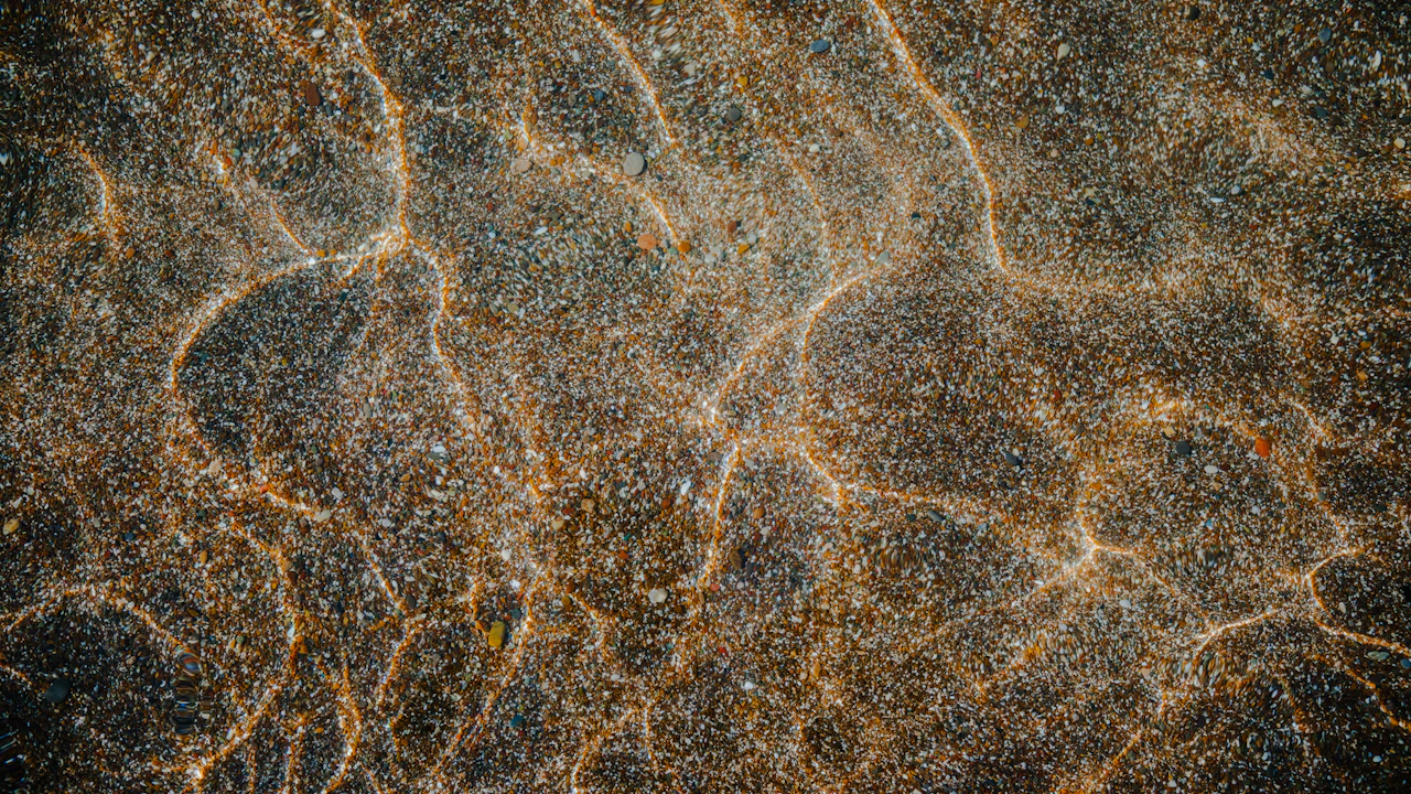 Rippled sand on a shallow seafloor with sunlight patterns