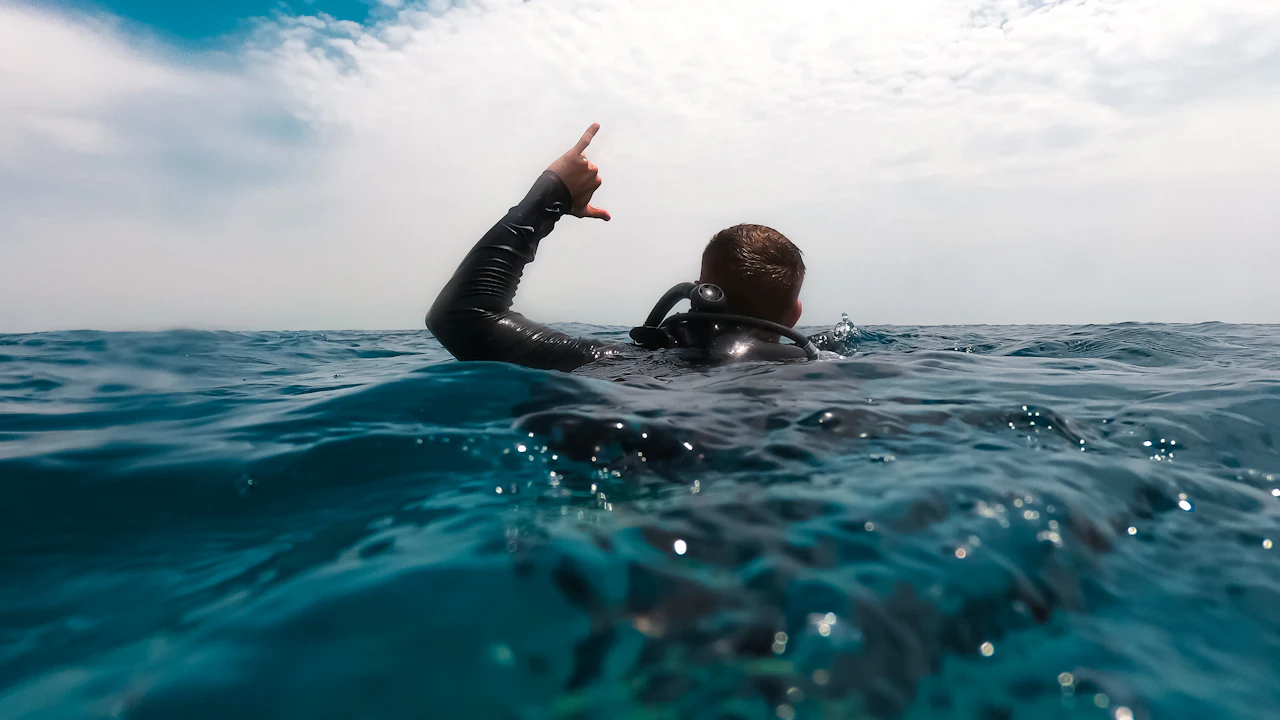 Diver at the surface pointing toward the sky