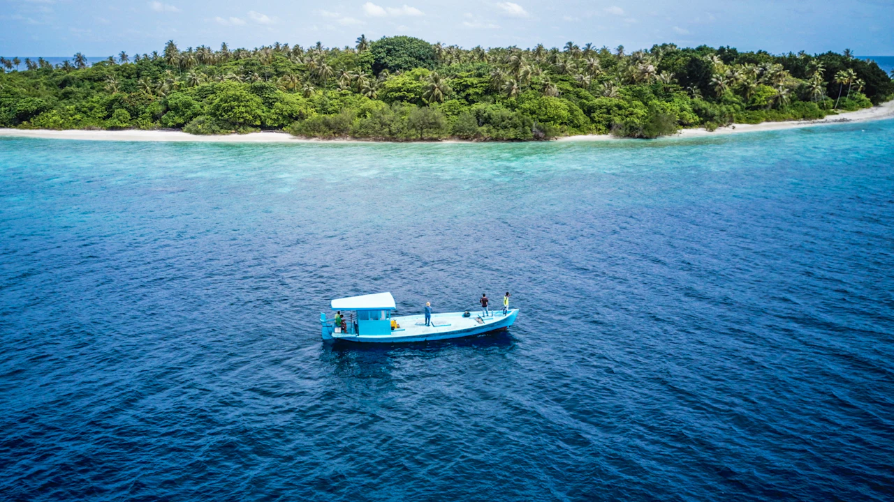 Small dive boat heading out across clear turquoise water in the morning