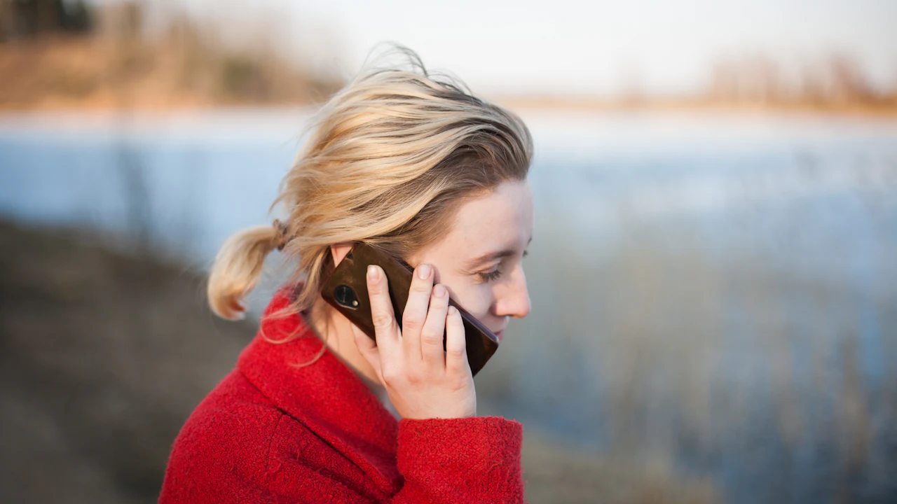 Woman in a red sweater making a phone call outdoors